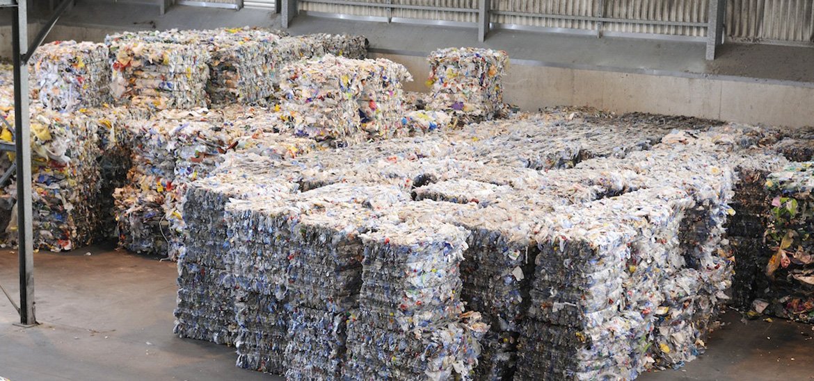 Vue aérienne de grands ballots de déchets plastiques colorés et compactés, prêts à être recyclés dans un entrepôt.